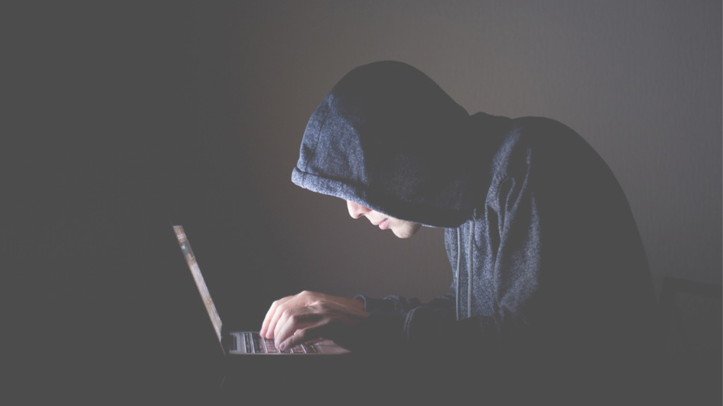 Junger Mann mit Kapuze vor einem PC