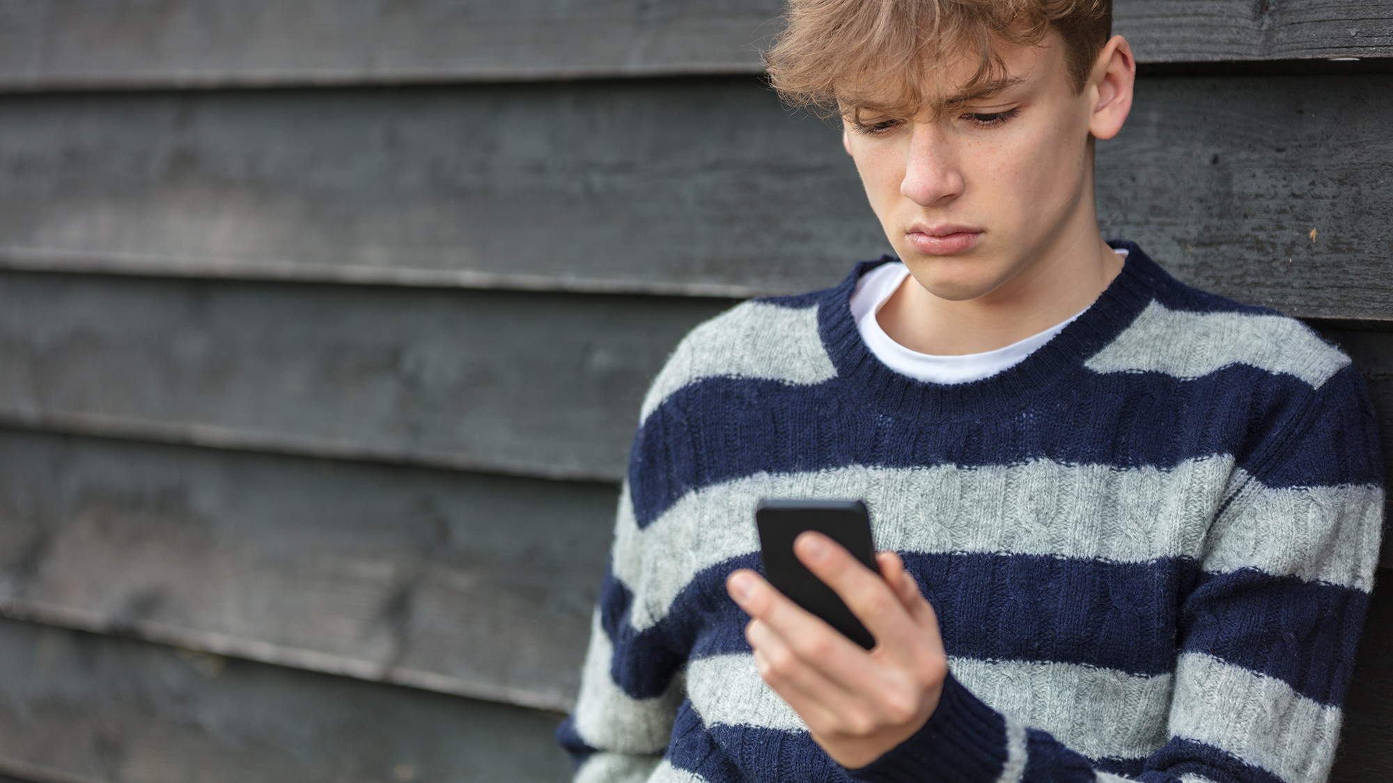 Junge sieht verzweifelt auf sein Handy