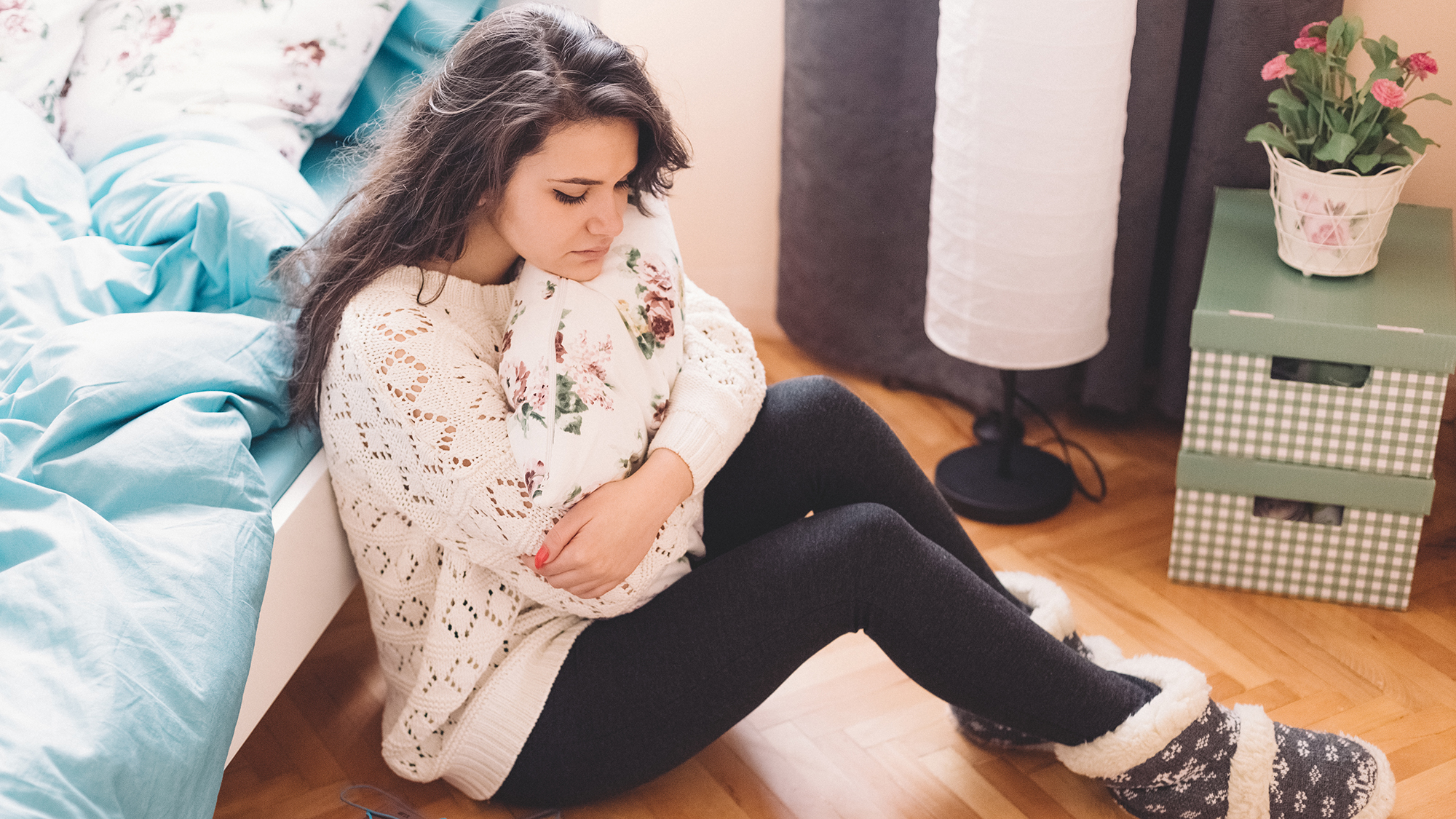 Mädchen sitzt am Boden und hält sich den Bauch