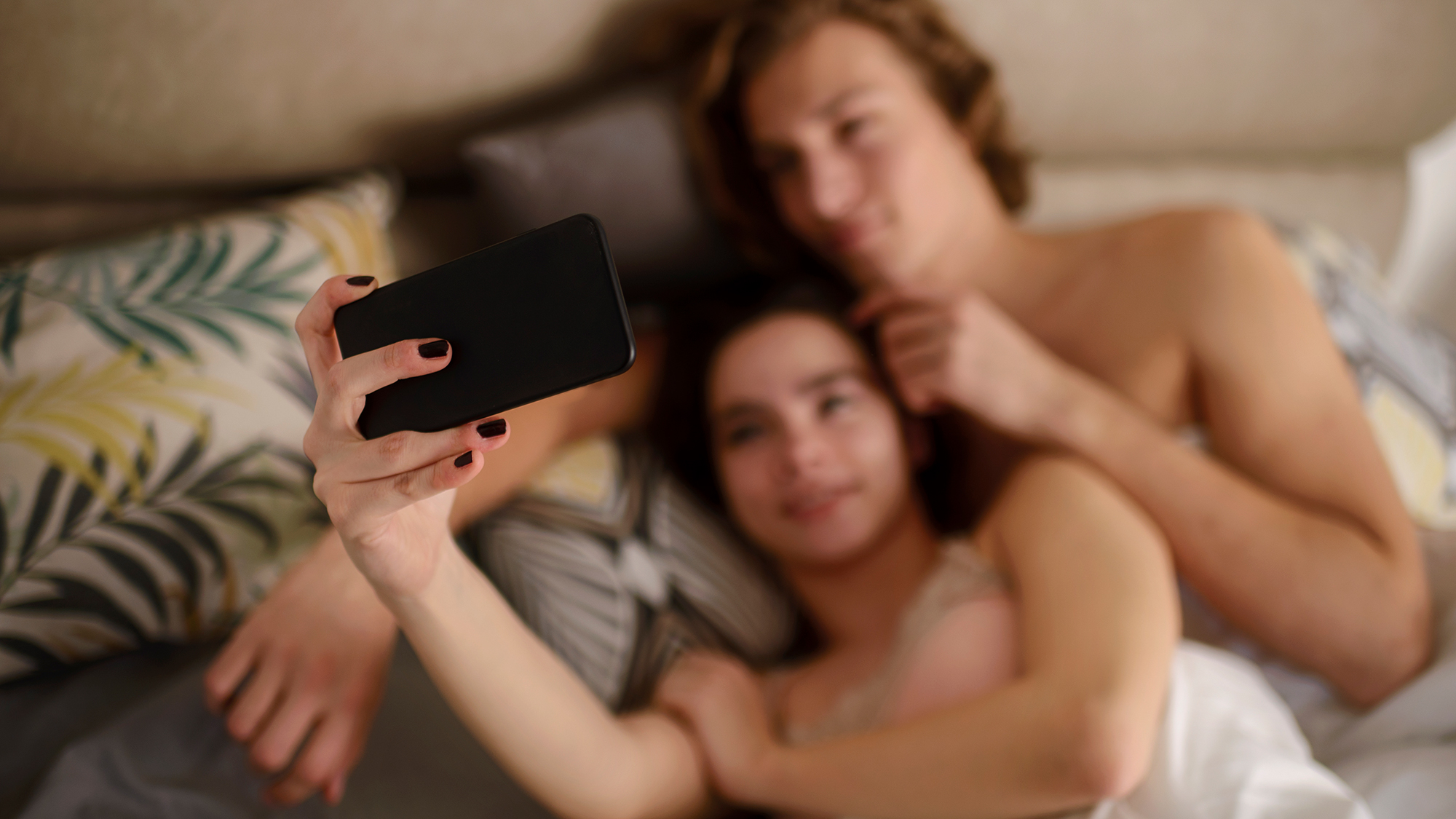 Ein Paar liegt im Bett und macht ein Selfie