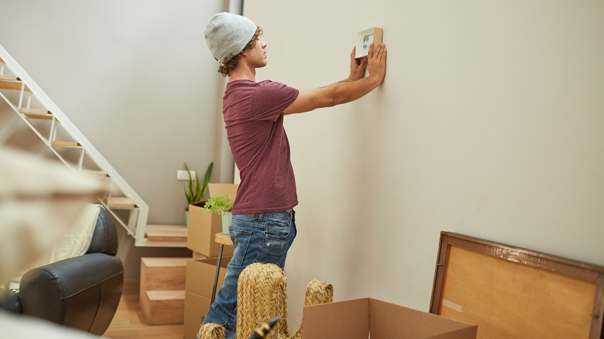 Junge hängt Bild in neuer Wohnung auf