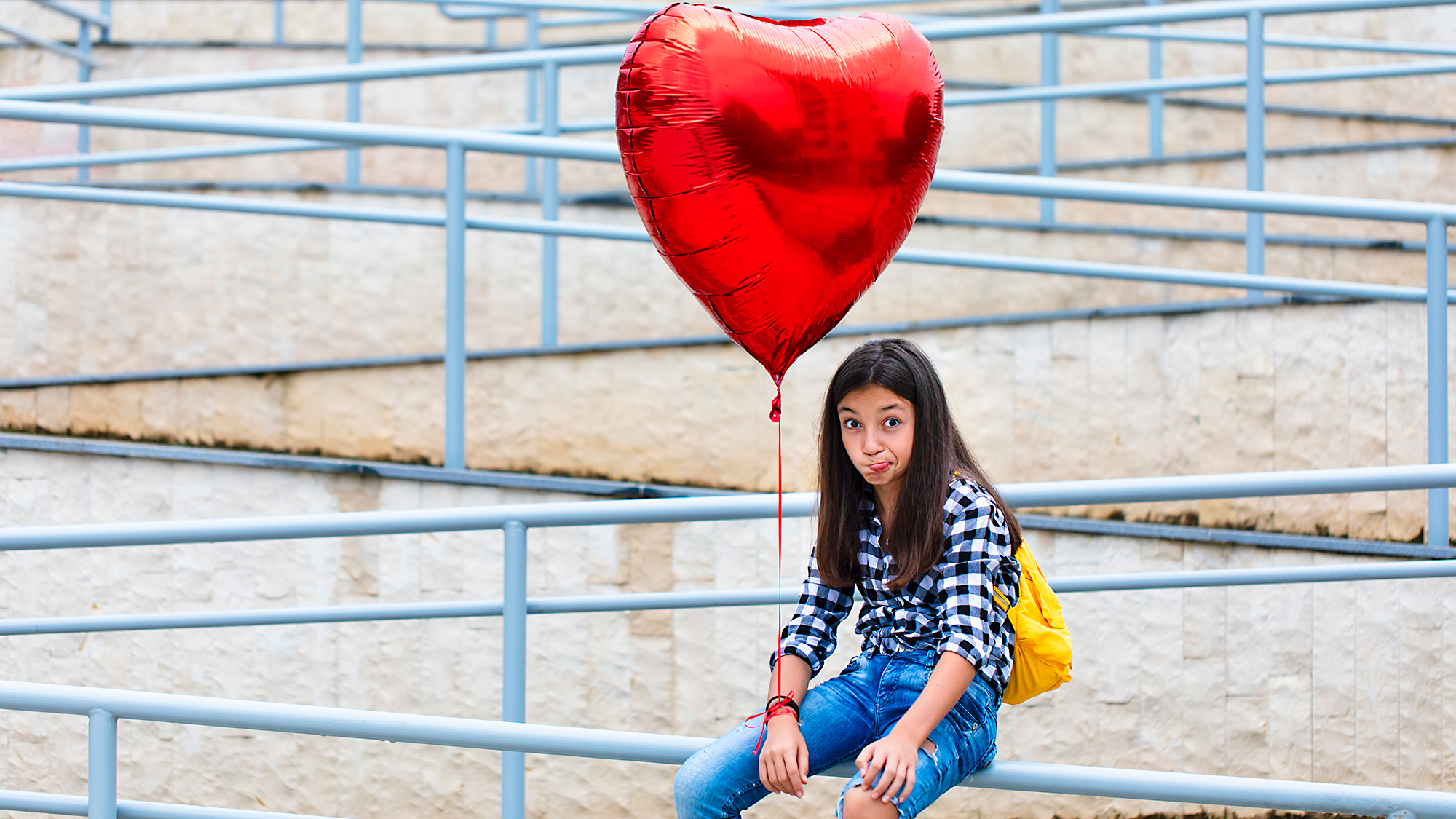 Mädchen auf Baustelle hält Herz-Luftballon