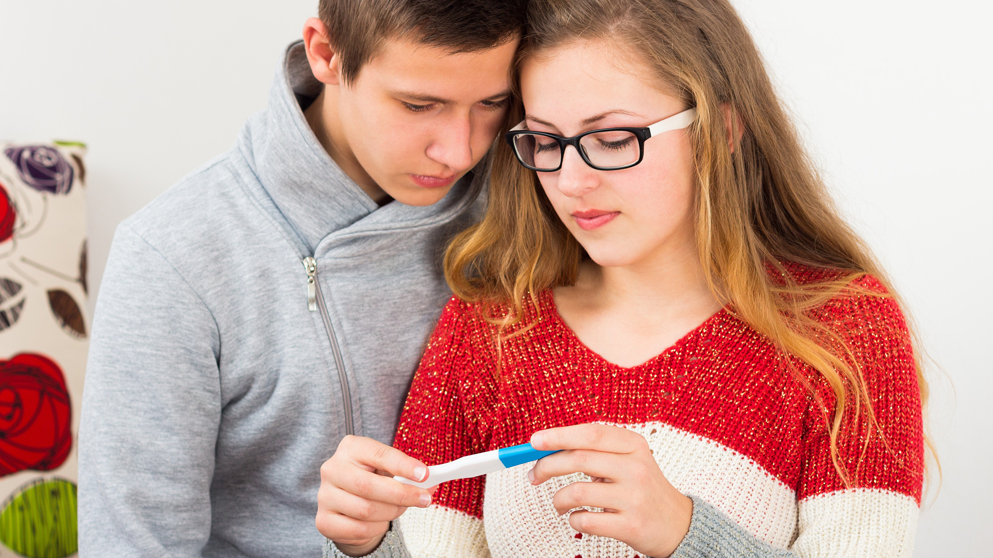 Junge und Mädchen schauen auf Schwangerschaftstest