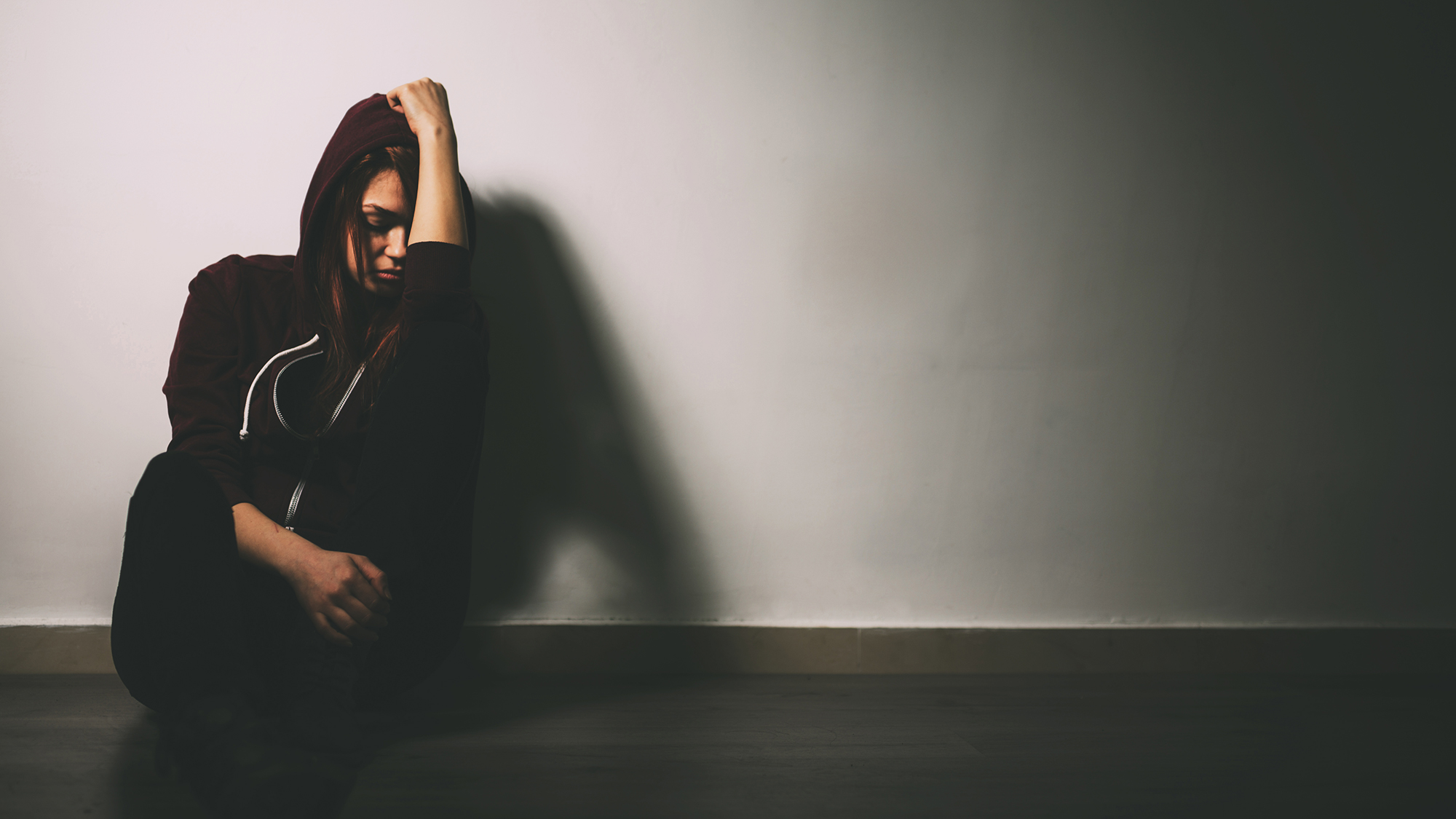 Mädchen sitzt traurig am Boden und stützt sich den Kopf