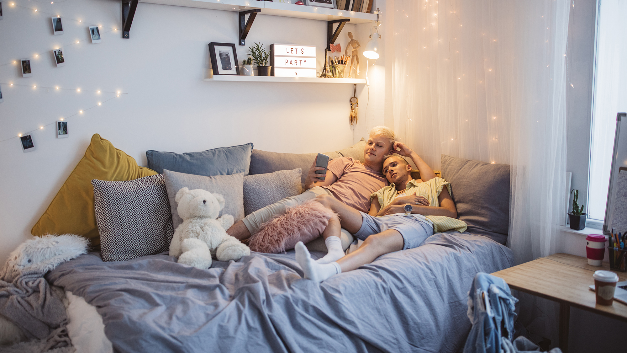 Pärchen liegt am Bett und schaut in ein Handy