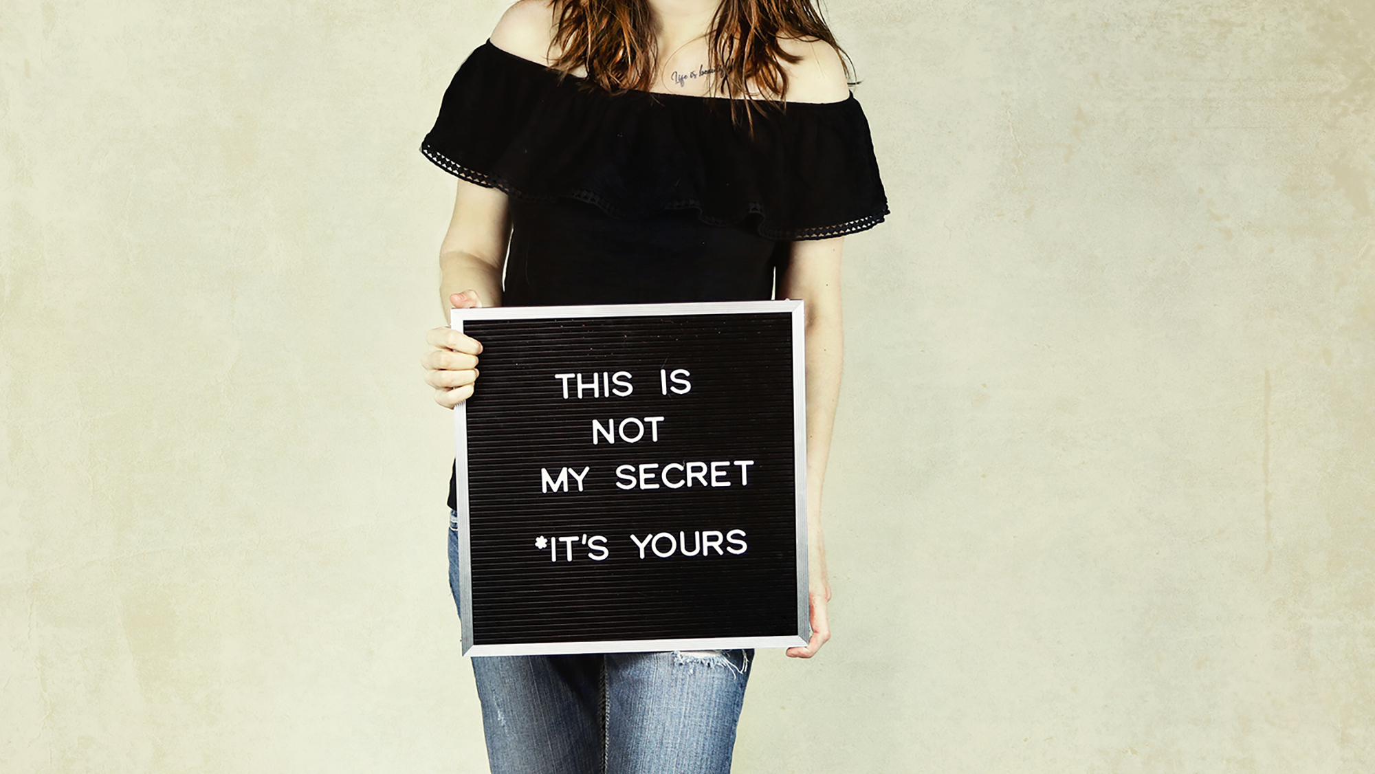 Mädchen hält Schild mit Aufschrift "this is not my secret it