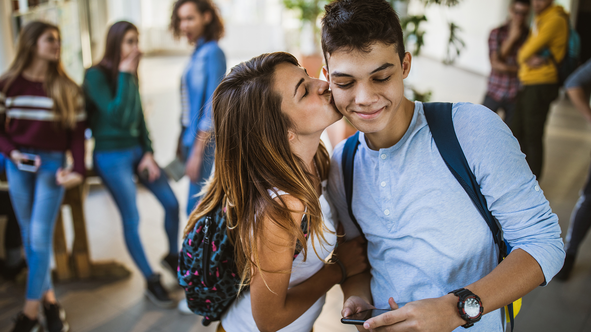Eine Schülerin gibt einem Schüler einen Kuss auf die Wange