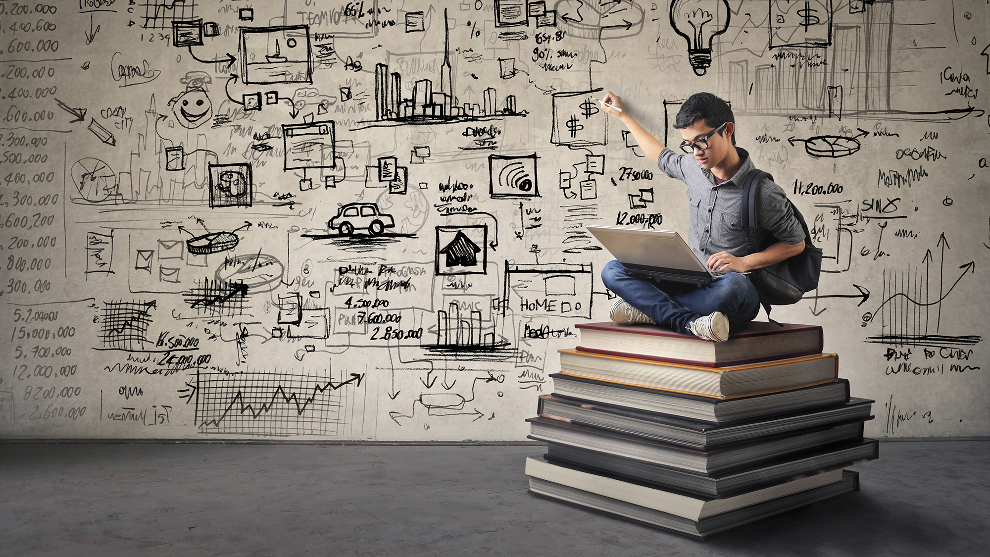 Junge sitzt auf großen Bücherstapel und zeichnet an die Wand