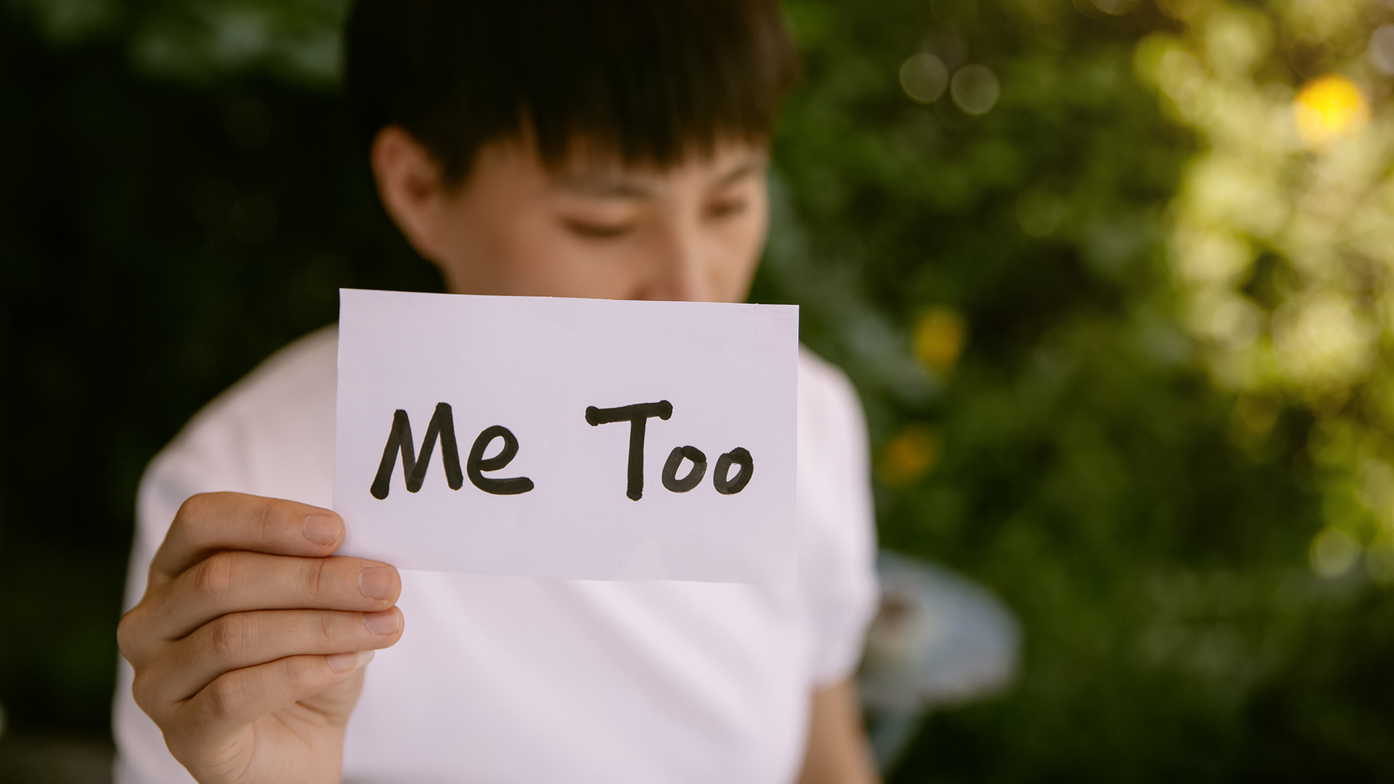 Junge hält Schild hoch mit Aufschrift "Me too"