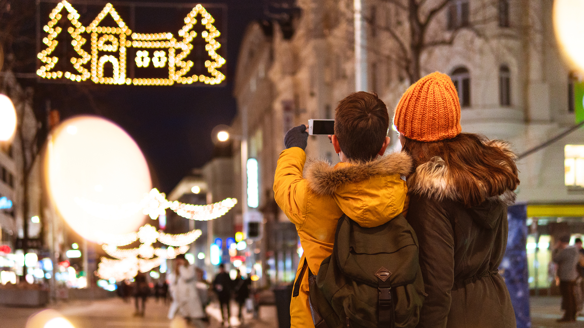 Zwei Jugendliche machen Selfie auf weihnachtlich beleuchteter Straße