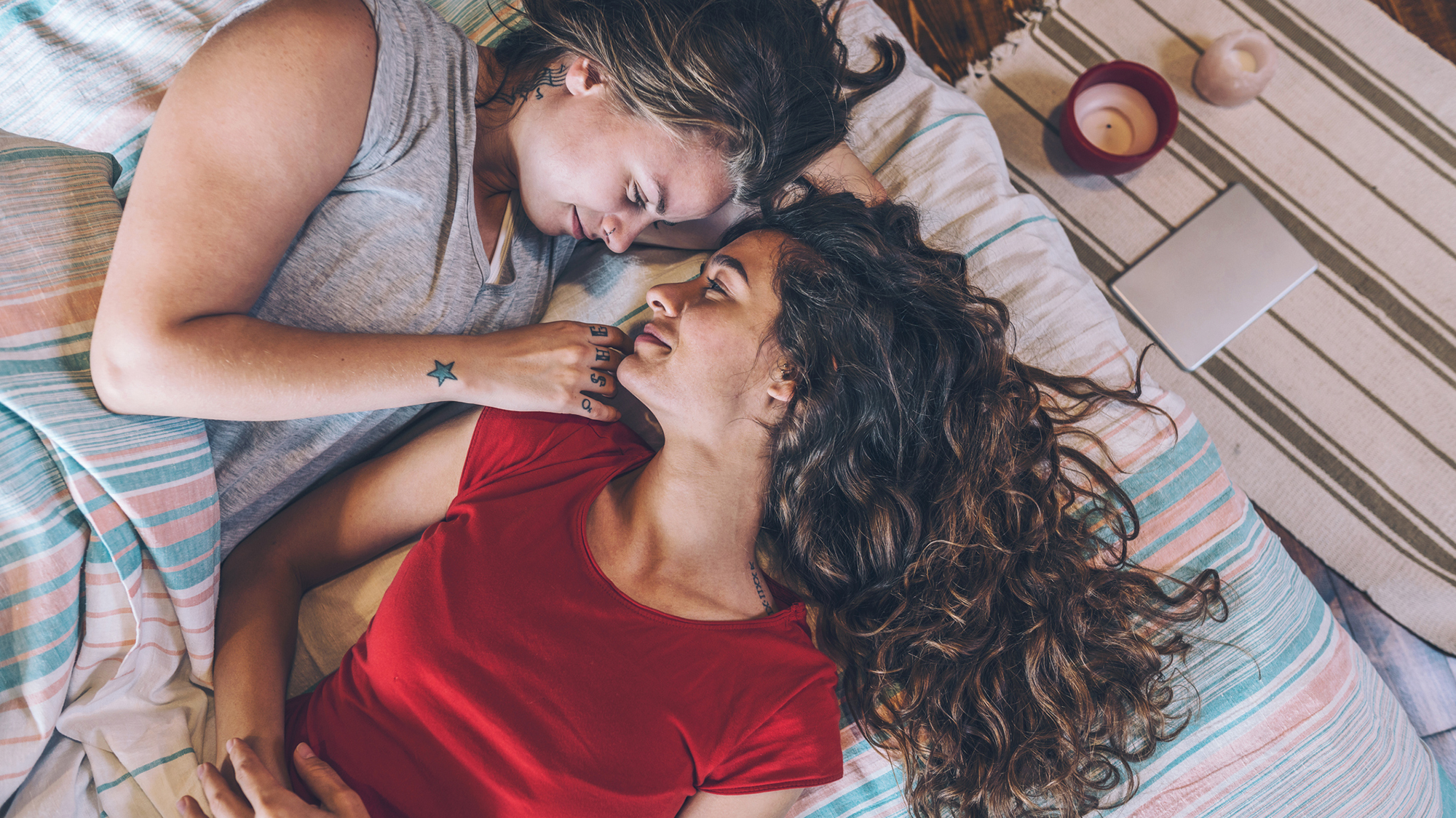 Zwei Mädchen liegen auf dem Bett und schauen sich an