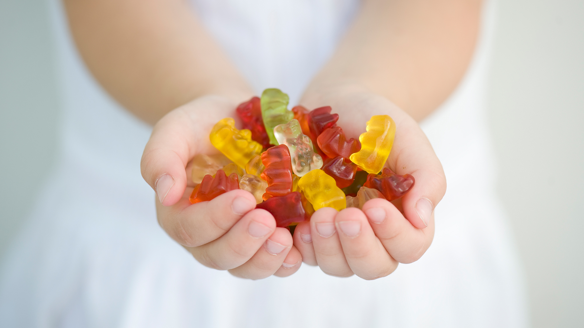 Kind hält Gummibärchen in den Händen