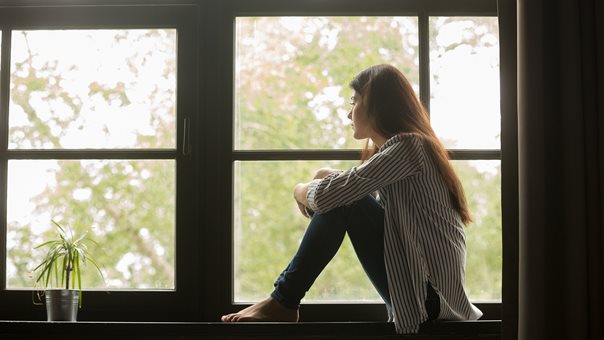 (c) iStockphoto.com/fizkes Mädchen sitzt auf Fensterbank und schaut traurig aus dem Fenster