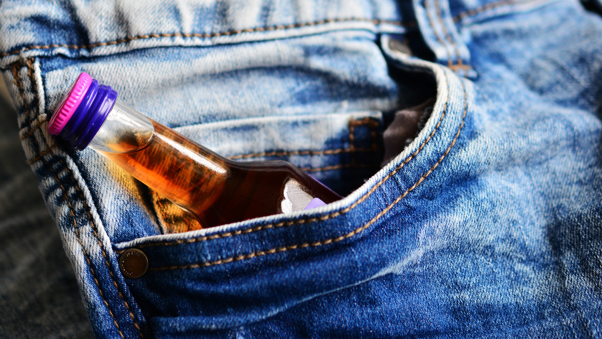 Jeans-Hosentasche in der sich eine kleine Flasche Alkohol befindet