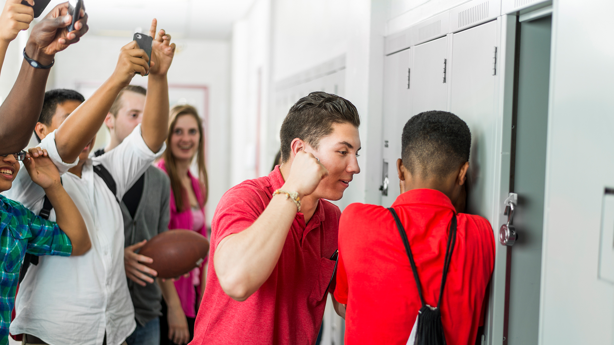 Junge schläft auf andren Junge ein, andere Schüler filmen mit Handy