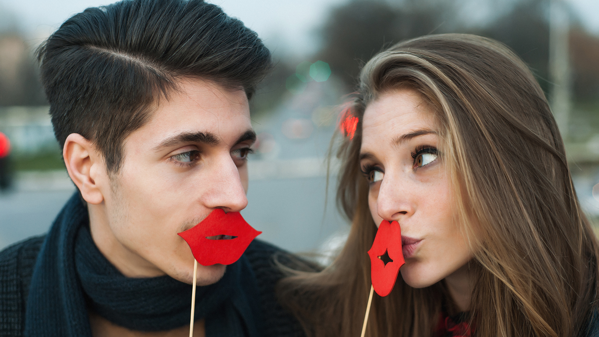 Ein Paar hält sich Kuss-Lippen aus Karton vor den Mund