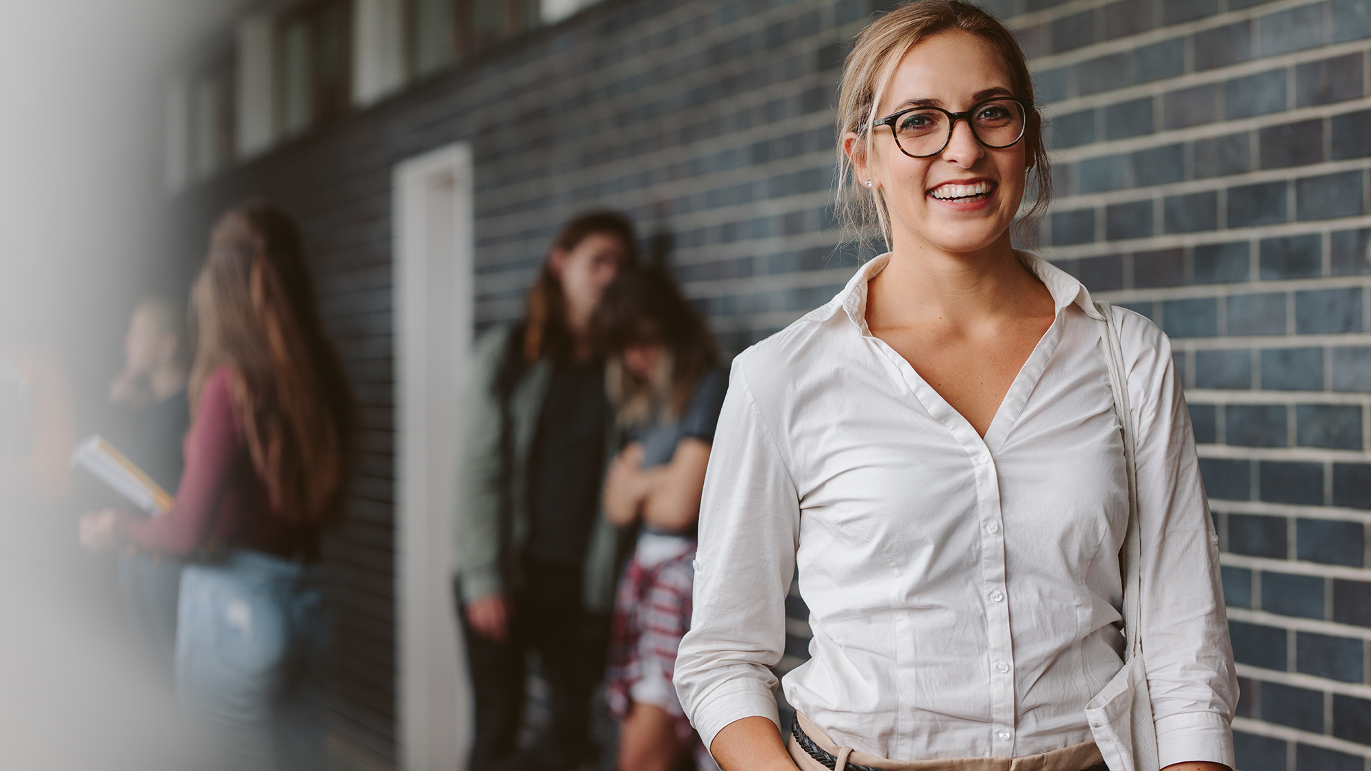 Lehrerin im Schulflur lacht in die Kamera