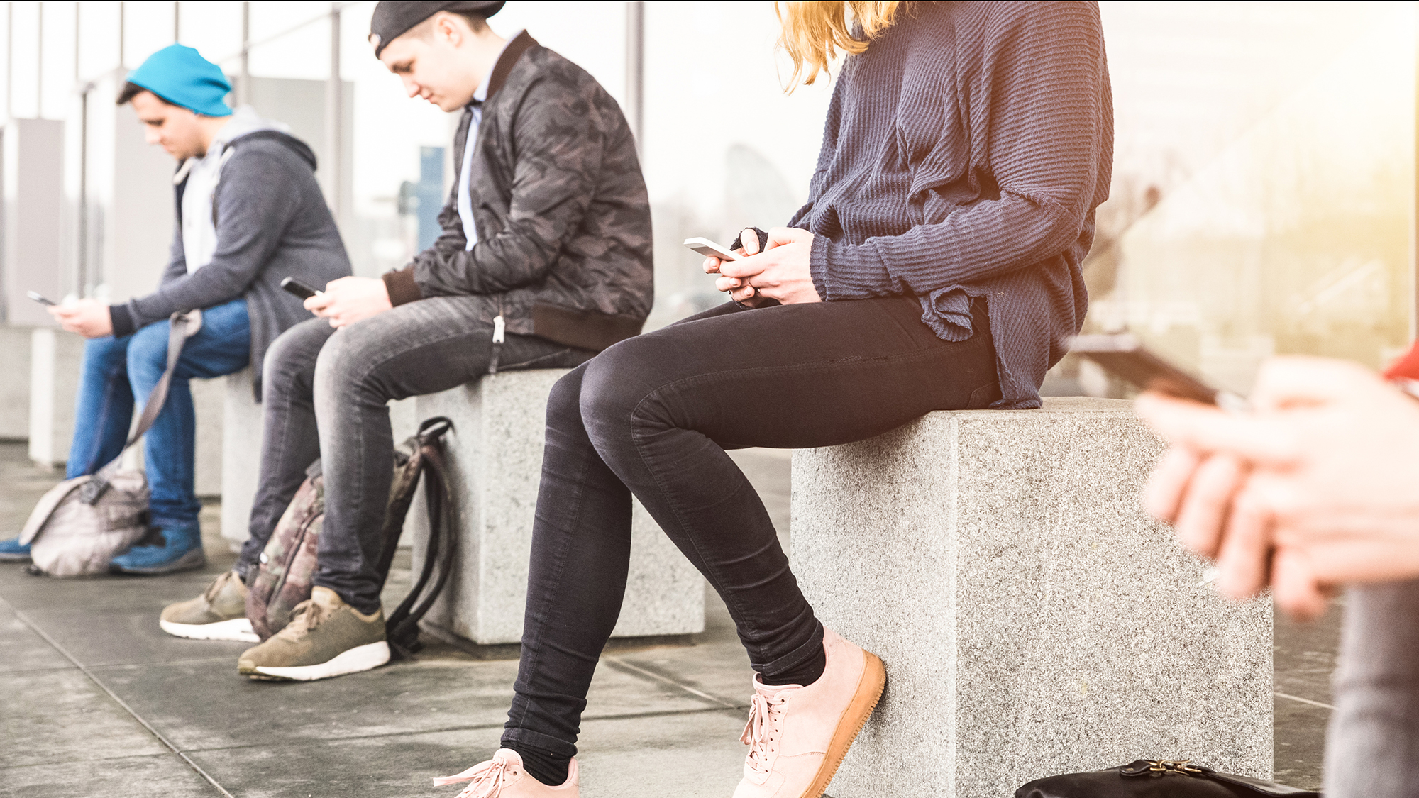 Jugendliche sitzen alle mit Handy da