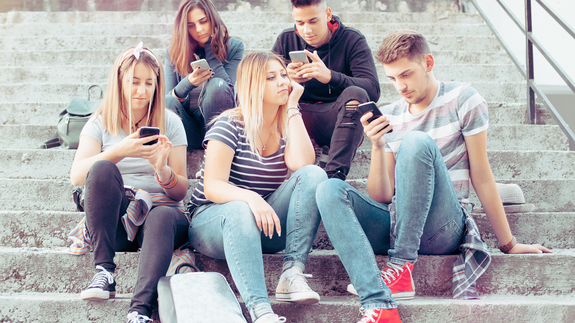 Jugendliche sitzten mit Handy auf einer Treppe