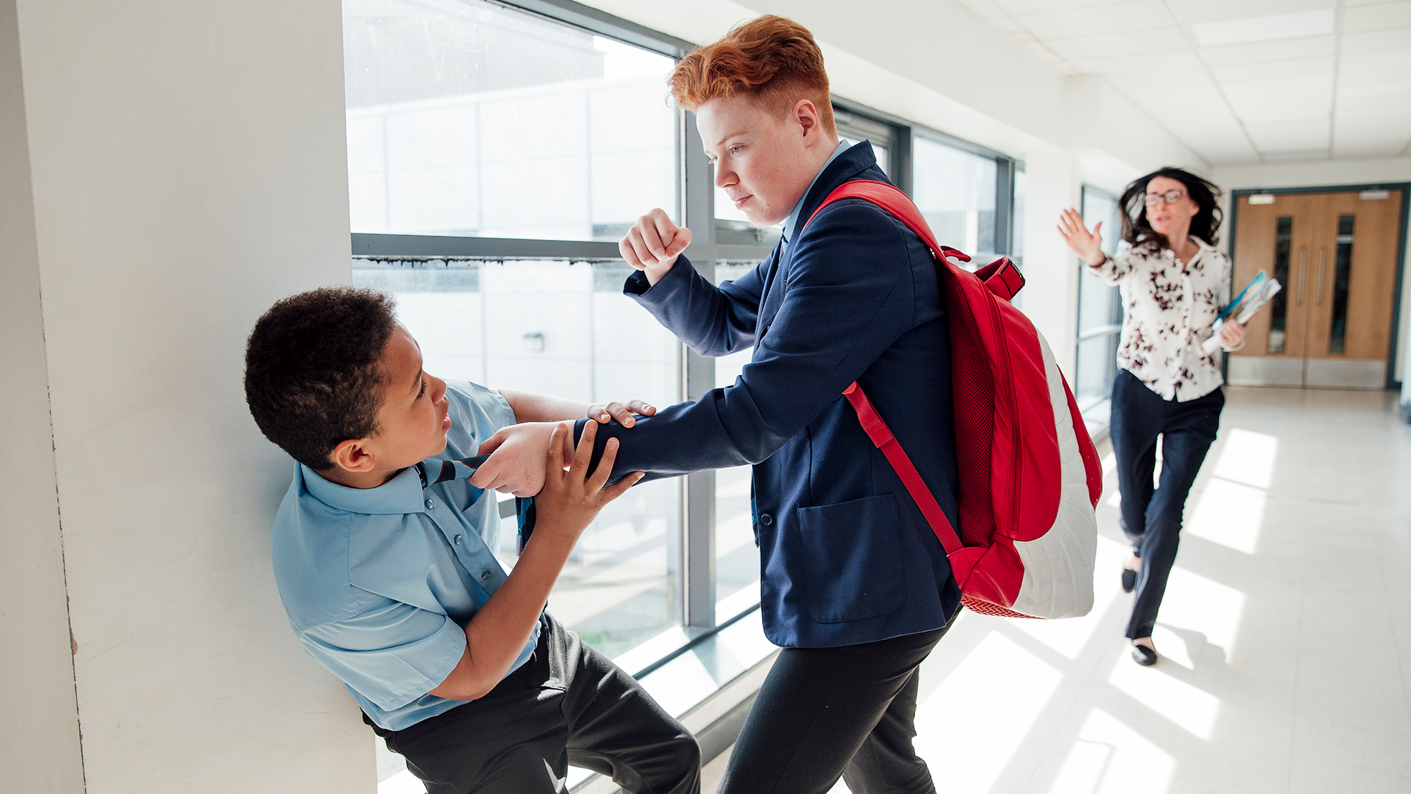 Junge packt anderen Jungen am Kragen, Lehrerin kommt angelaufen