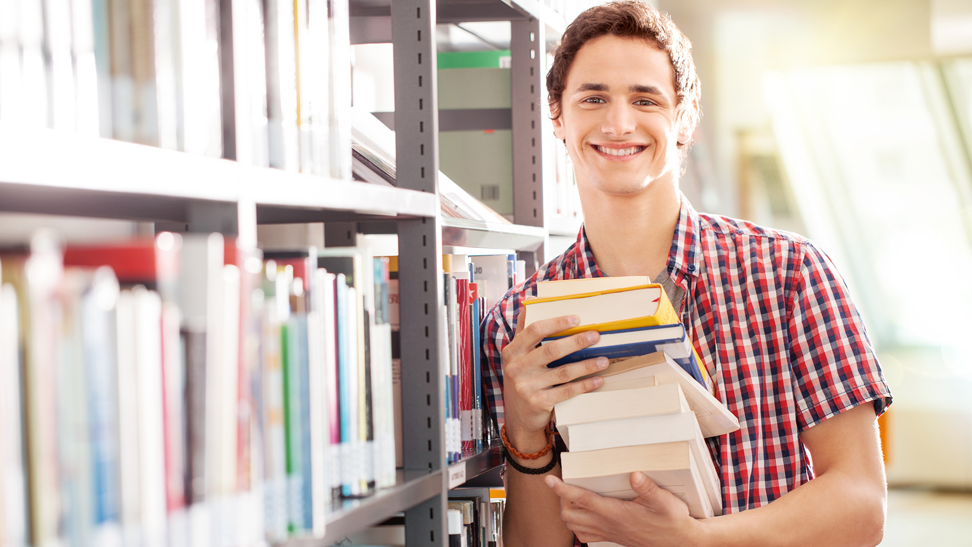 Junge steht in Bibliothek mit vielen Büchern