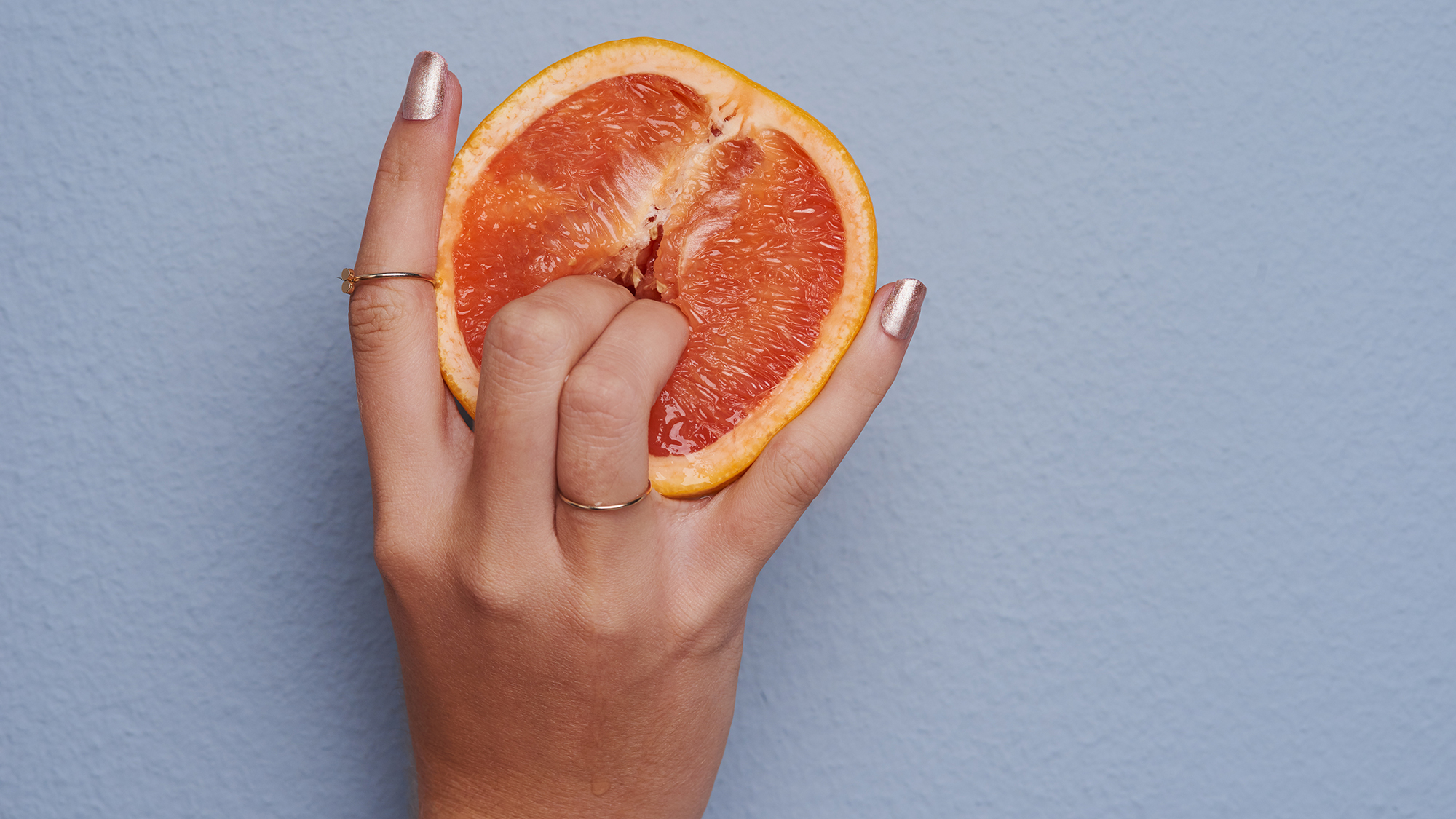 Frau bohrt Finger in eine Orange