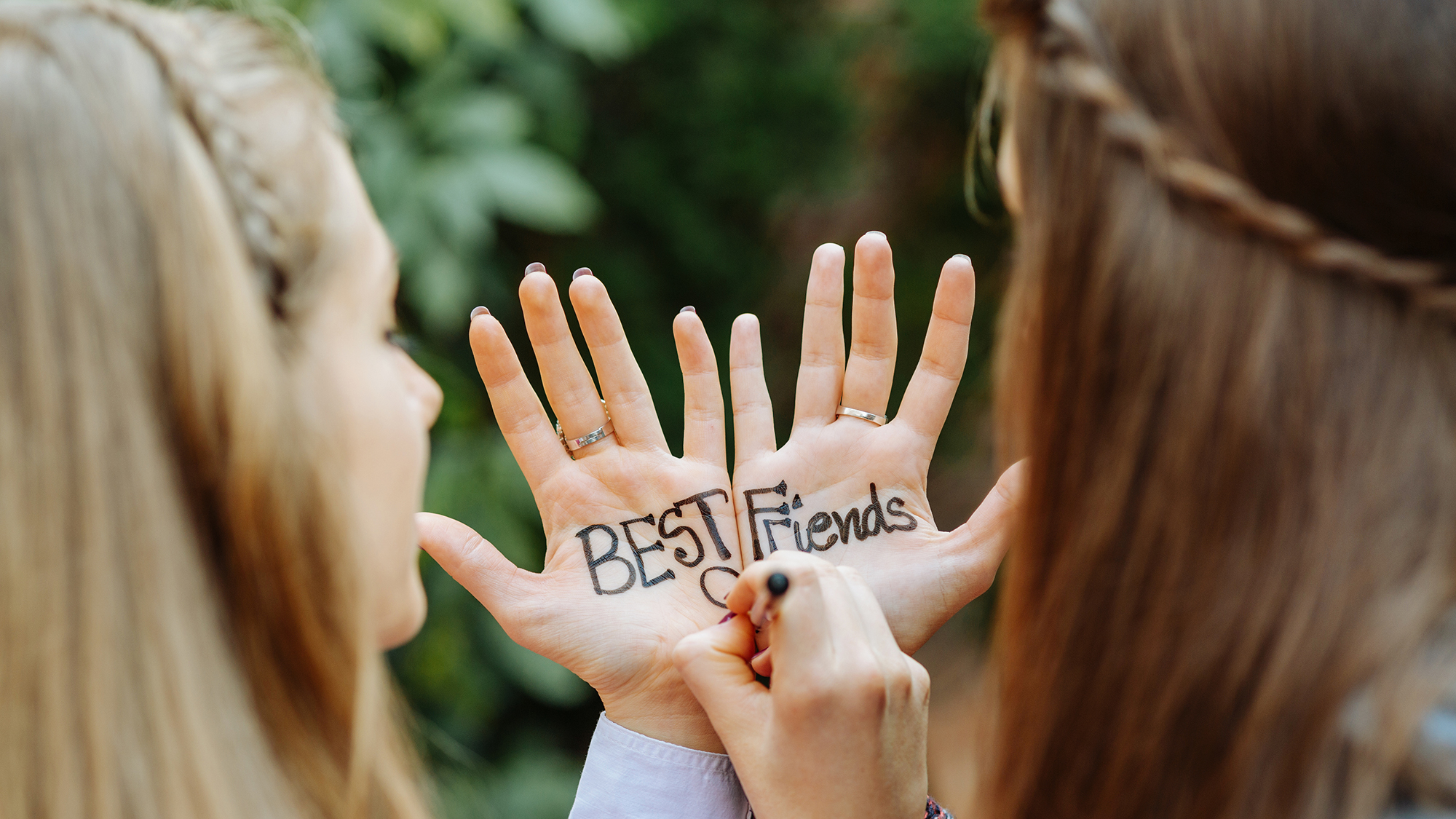 Zwei Mädchen schreiben "Best Friends" auf ihre Hände