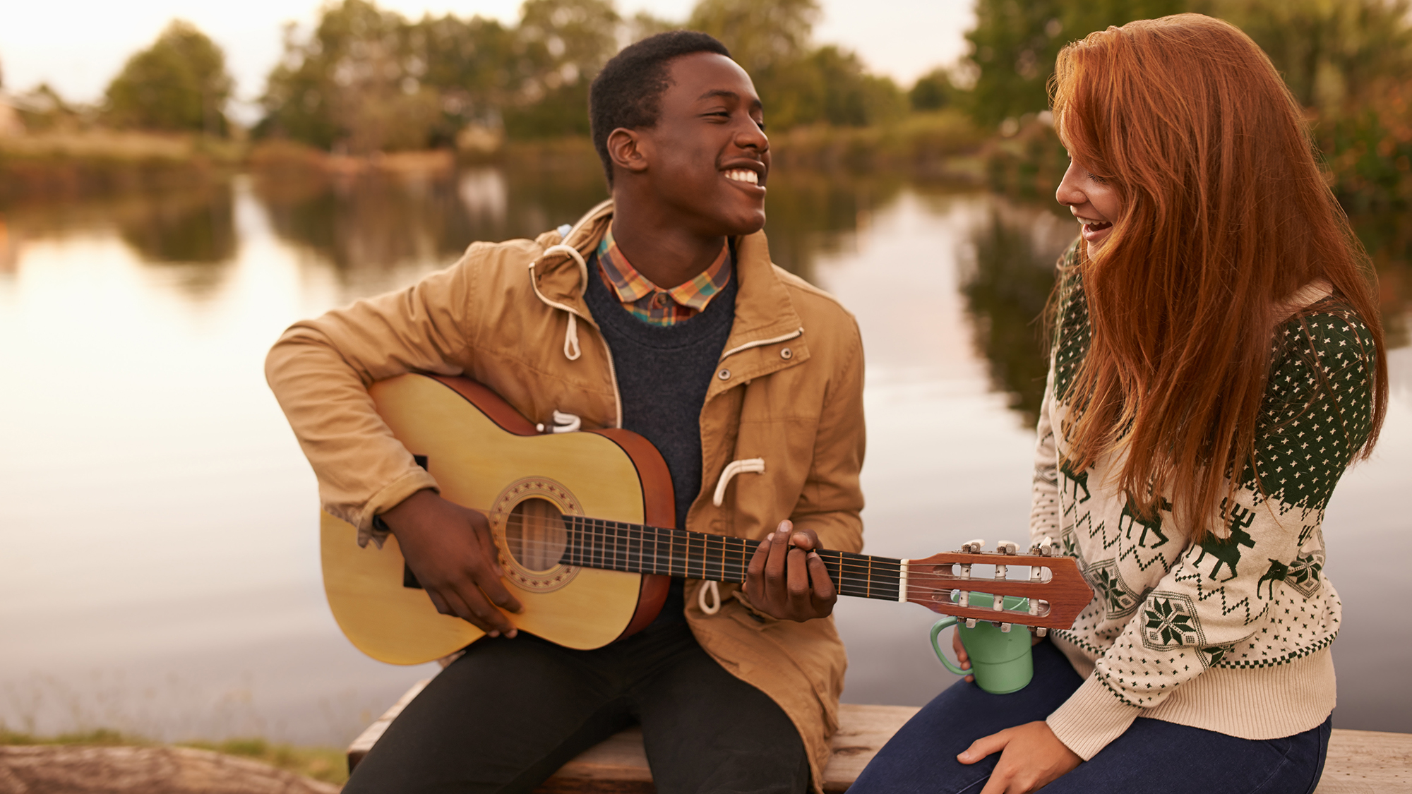 Bursch mit Gitarre singt und schaut Mädchen in die Augen