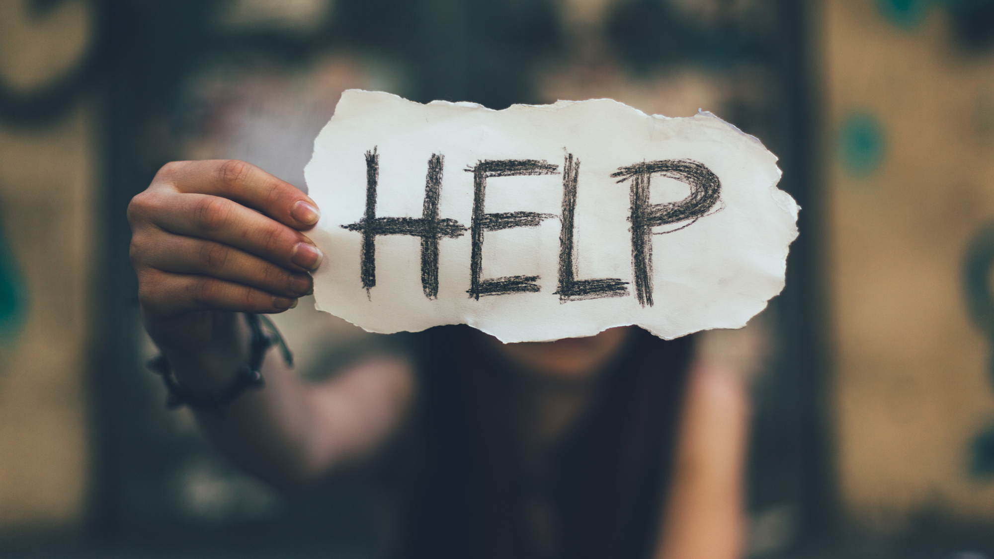 Mädchen hält Zettel mit Aufschrift "HELP"
