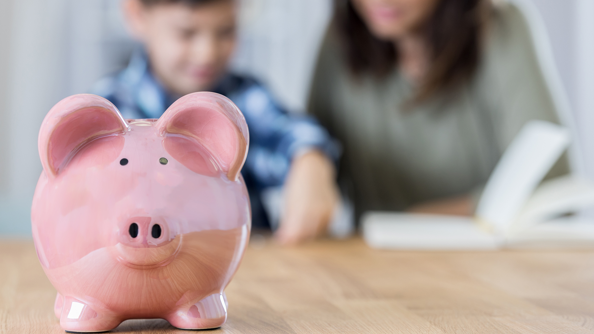 Sparschwein auf Tisch im Hintergrund Mutter mit Sohn