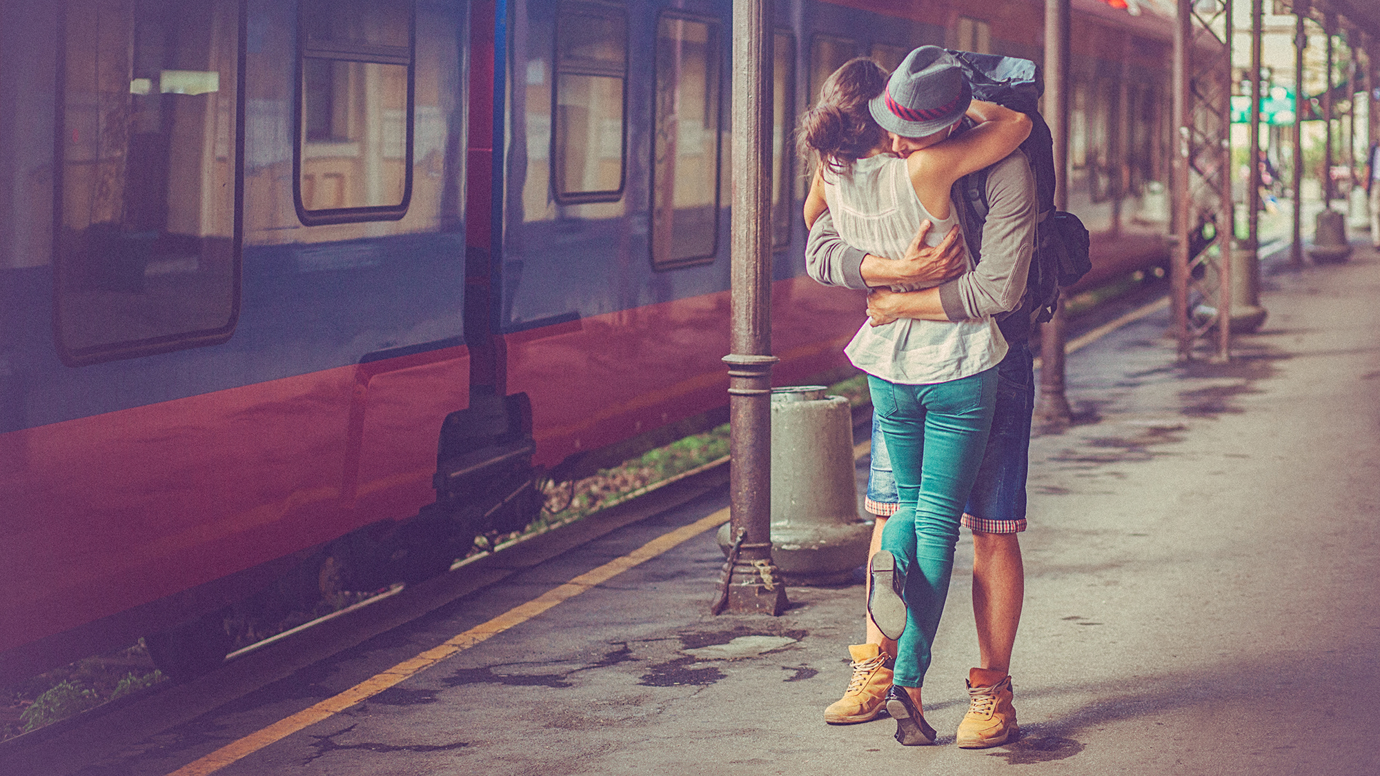 Paar umart sich strahlend am Bahnsteig