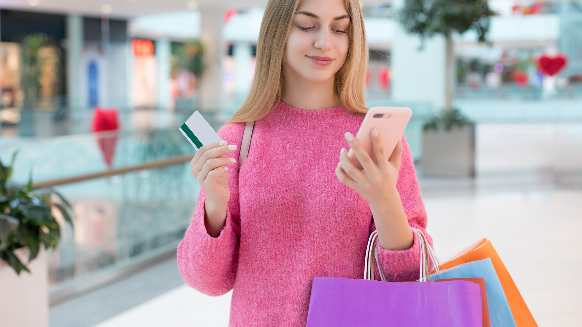 Mädchen mit Einkaufstaschen, Handy und Bankkarte in den Händen