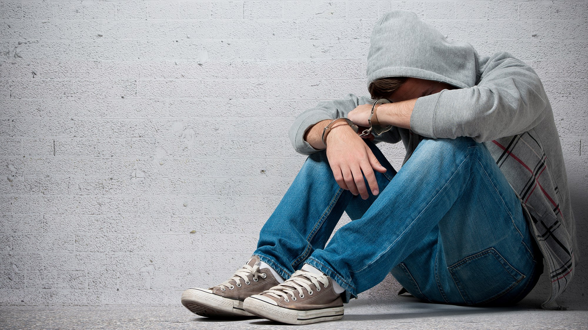 Junge sitzt mit Kopf im Schoß auf dem Boden