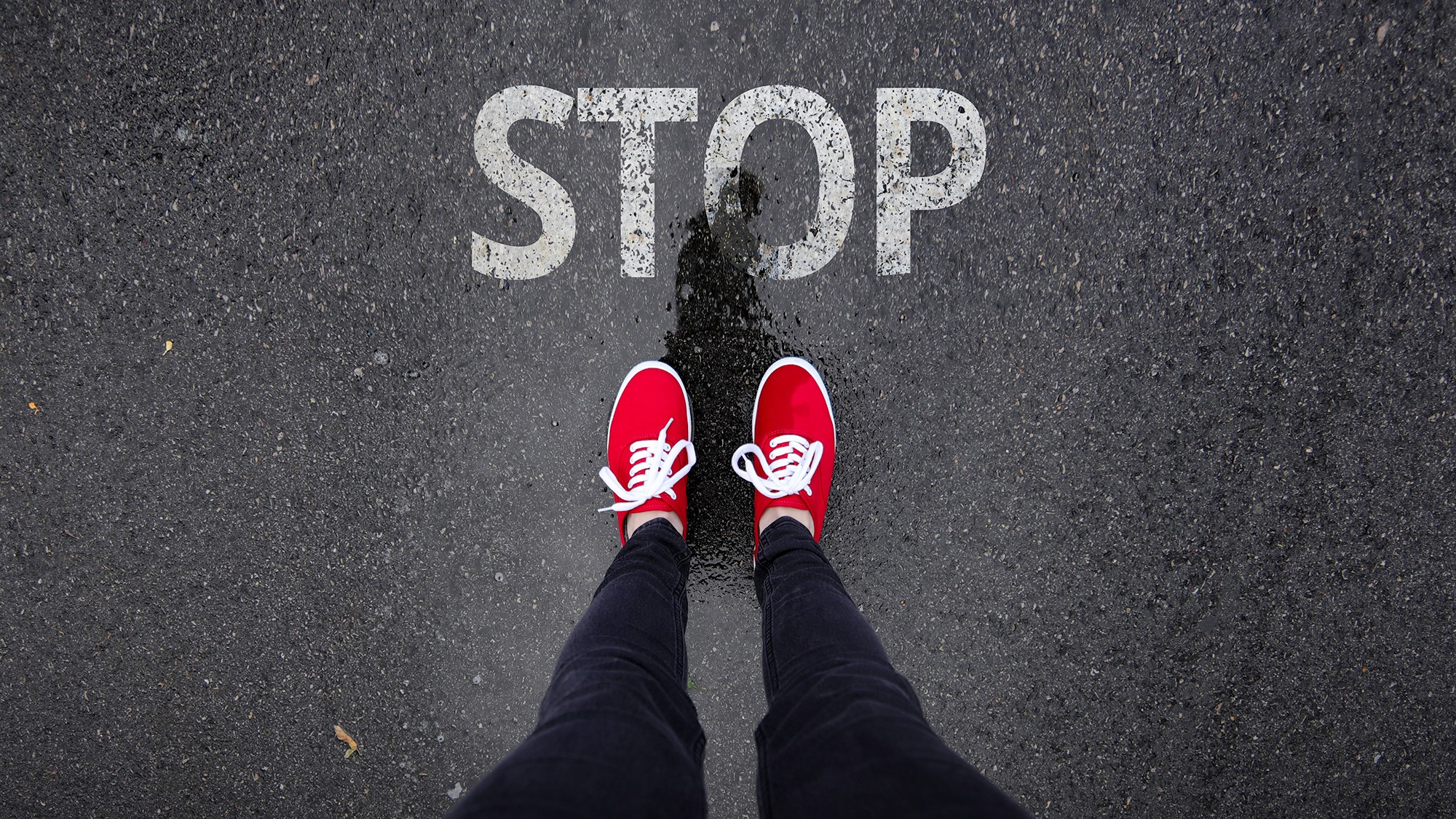 Mädchen oder Bursch steht auf "Stop", das auf die Straße gemalt wurde