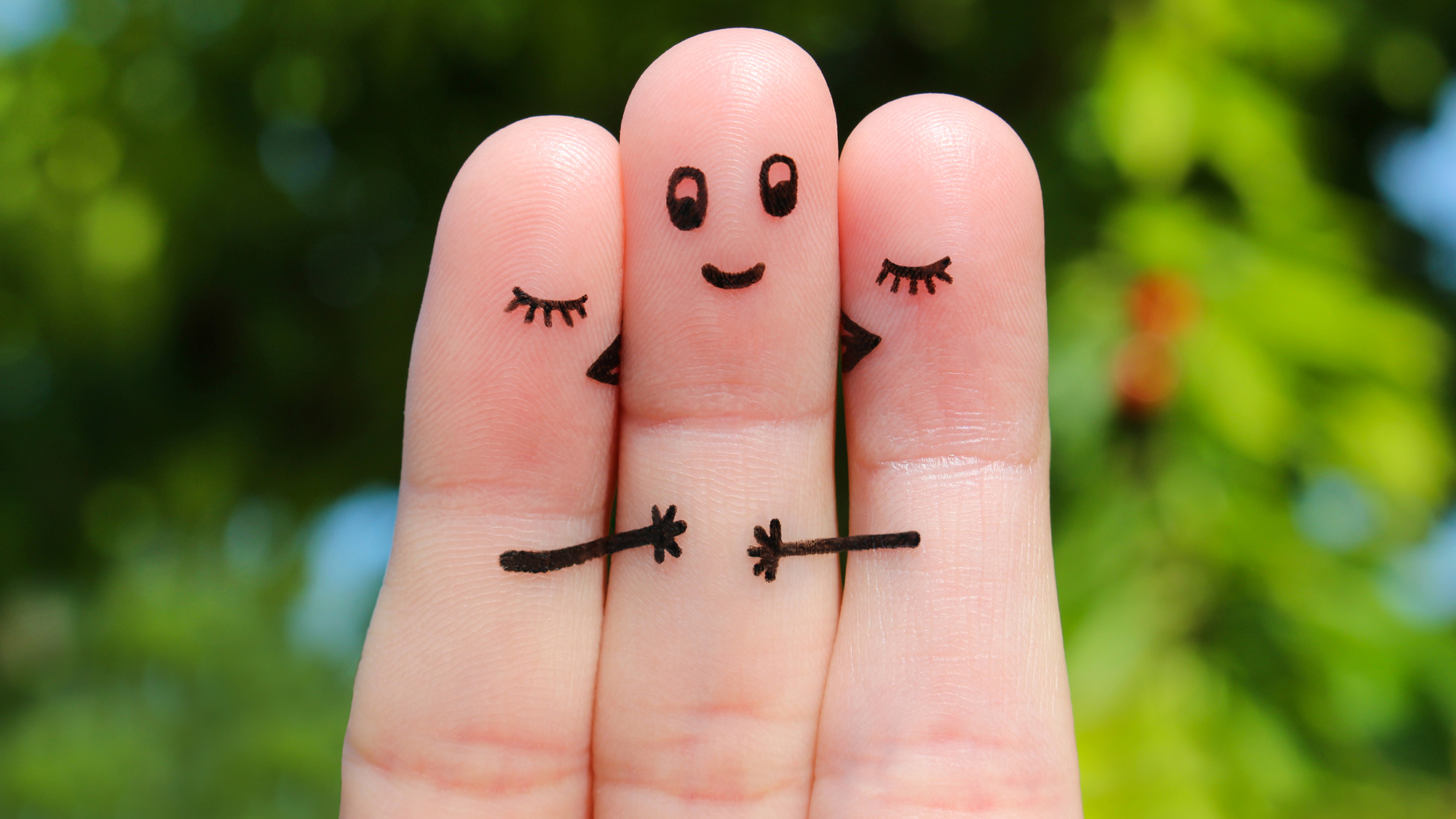 Drei Finger mit einem aufgemalten Gesicht, die sich scheinbar umarmen