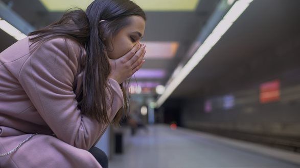 Mädchen sitzt am Bahnhof und hat ihre Augen wegen Sorgen geschlossen